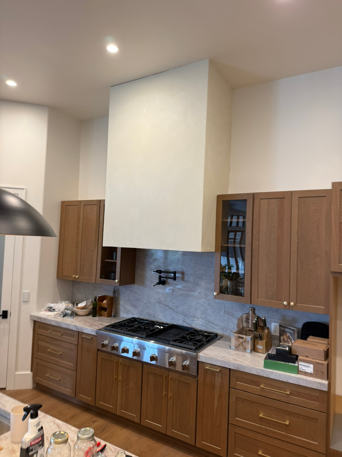 Custom marble effect range hood and backsplash in a warm wood kitchen